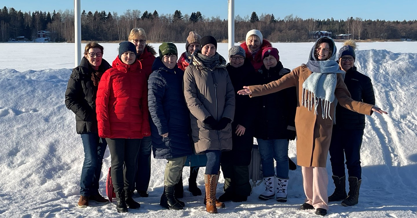 En frivillig inom Röda Korset och deltagarna i Röda Korsets kurs på ukrainska ler tillsammans i ett vinterlandskap.